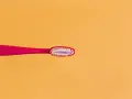 Różowa szczoteczka z pastą, która zawiera fluor. Czy fluor jest szkodliwy? Dyskusja trwa, ale pasta pomaga chronić zęby.