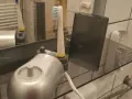 Pierwsze ładowanie szczoteczki elektrycznej. Nowa szczoteczka z ładowarką i etui na półce w łazience.