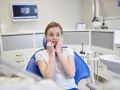 Przerażona dziewczyna w gabinecie dentystycznym, bojąca się, że ma siny ząb.