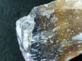 Kryształ fluorytu, w którym jest fluor, mieni się odcieniami żółci i błękitu, ukazując swoją krystaliczną strukturę.