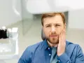 Mężczyzna z bólem zęba po zatruciu, szuka pomocy.