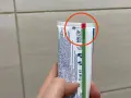 Oznaczenia past do zębów na tubce Colgate. Czerwone kółko podkreśla górną część opakowania.