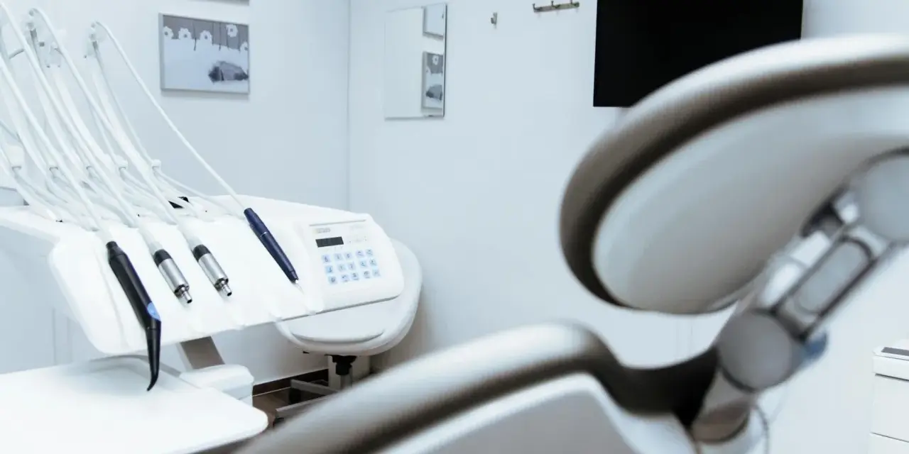 Gabinet stomatologiczny z fotelem i narzędziami. W tle monitor i lustro. Czystość i sterylność, jak po użyciu środka z chlorheksydyny diglukonianem.