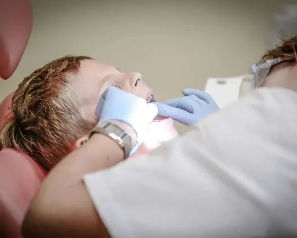 Chłopiec u dentysty, który bada jego zęby. Może to być związane z bólem podniebienia przy zębach górnych.