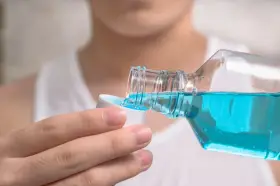 Niebieski płyn do płukania jamy ustnej, z butelki przelewany do nakrętki. Idealny do odświeżenia oddechu.